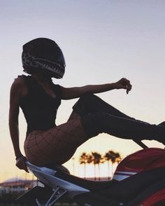 a woman sitting on top of a motorcycle wearing fishnet tights and a helmet