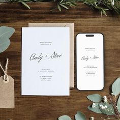 the wedding stationery is laid out on a table with greenery and paper tags