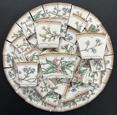 a plate with flowers on it sitting on top of a black tablecloth covered surface