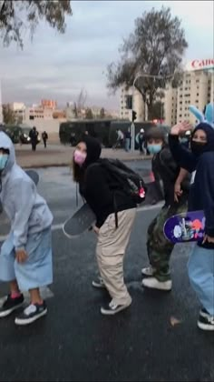 a group of people with skateboards in the middle of an intersection wearing face masks