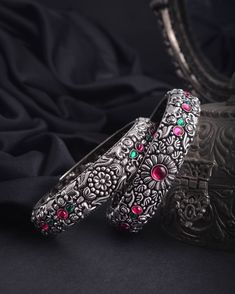 Add a dash of royalty to your outfit with these stunning Bollywood stone bangles. The intricate details of flowers, leaves, stones, and other designs make these kolhapuri stone bangles with antique floral designs more authentic. Elegant and positive vibes radiate from each aspect of this German silver jewelry. Vastrabhushan is the only place to get these satiny bangles, available in 9 different designs. You're set to take center stage when you wear these Indian bangles with your formal attire or Antique Silver Bangles, Festive Silver Jeweled Bangle, Bohemian Gemstone Wedding Bangle, Bohemian Silver Bangle For Celebration, Traditional Flower Jewelry For Diwali, Traditional Flower-shaped Jewelry For Diwali, Traditional Festive Flower Jewelry, Traditional Silver Jeweled Bracelets, Festive Flower Jewelry For Diwali