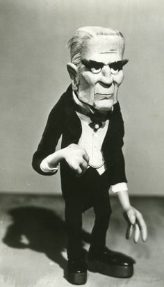 an old black and white photo of a man in a tuxedo pointing at something