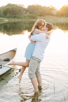 a man and woman hugging in the water near a boat with their arms around each other