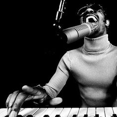 a man singing into a microphone while sitting at a keyboard with his hands on the keys