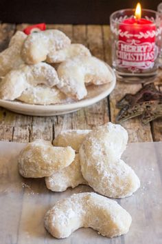 powdered sugar cookies sitting on top of a wooden table next to a lit candle