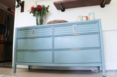 a blue dresser with gold handles and drawers