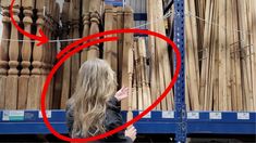 a woman standing in front of stacks of wooden pipes with a red circle over her face