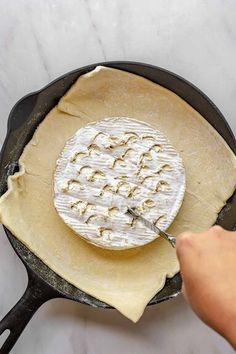 a skillet with cheese being made in it and someone using a spatula to stir them