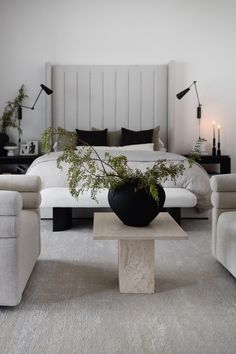 a bedroom with a bed, two chairs and a coffee table in front of it