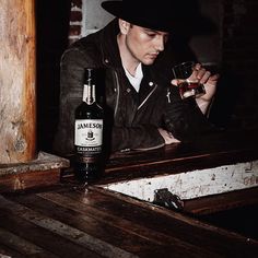 a man sitting at a table with a bottle of wine and a glass in his hand