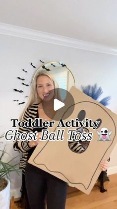 a woman holding up a cardboard ghost ball to her face with text reading toddler activity ghost ball toss