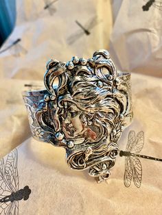 Art Nouveau style cuff.  Magnificent hand crafted Alphonza Mucha style Lady Cuff. From MyElegantThings Design Studio"  Antique silver plated over brass cuff. Engraved cuff with gorgeous flowers and vines and leaves. Vintage style very limited edition Cuff is an engraved and gorgeous garden piece. 1 inch width. Woman piece is 1-1/2 inches. Gorgeous and what a statement. Ornate Silver Cuff Bracelet, Artistic Silver Cuff Bracelet, Artistic Silver Cuff Bracelet Bangle, Artistic Silver Cuff Bangle Bracelet, Artistic Silver Bangle Cuff Bracelet, Artistic Silver Bangle Bracelet, Nickel-free Silver Cuff Bracelet For Wedding, Artistic Silver Bangle Bracelets, Silver Nickel-free Cuff Bracelet For Wedding