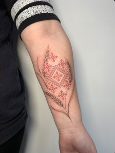 a person with a tattoo on their arm holding onto a hand that has a cross and flower design on it