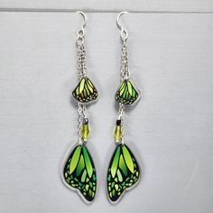 Butterfly Wing Earrings Green Monarch Butterfly Wings Earrings Long Dangle Drop Earrings Magical Fairy Wing Earrings Colorful Wing Earrings I ship super fast.  These super fun lightweight earrings are so pretty. The beads are wire wrapped and connected to the chain.  The wings are connected to the chain.  They are all gathered on a jumpring and connected to the ear wires. The wings are made of resin.  They are double-sided.  The beads are glass crystals.  The chain is non-tranish silver plated and the ear wires are Sterling Silver.  They ship with rubber backs to prevent loss in a delightful organza bag perfect for gift giving. Whimsical Butterfly Earrings With Ear Wire, Whimsical Metal Dangle Earrings, Whimsical Green Dangle Jewelry, Whimsical Green Nickel-free Jewelry, Fairycore Dangle Earrings With Ear Wire, Nickel-free Fairycore Earrings For Jewelry Making, Green Fairy Earrings For Gift, Fairy Style Drop Earrings For Gifts, Fairycore Nickel Free Earrings As Gift