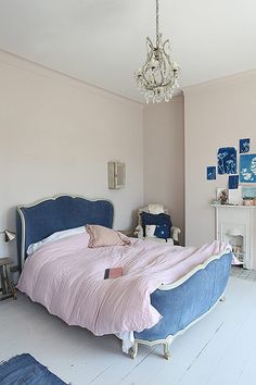 a bedroom with pink walls and blue bedding, chandelier hanging from the ceiling