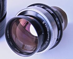 a close up of a camera lens on a white surface with a black cup in the background