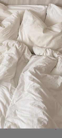 an unmade bed with white sheets and pillows