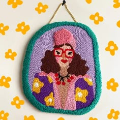 an embroidered purse hanging on a wall with flowers in the background