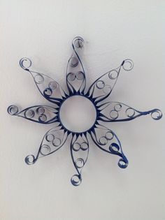 a decorative metal wall hanging on the side of a white wall with swirly designs