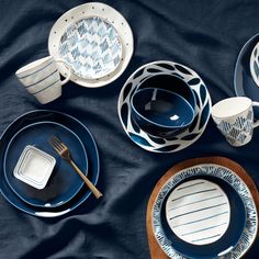 blue and white dinnerware is laid out on a bed