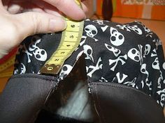 someone is measuring the inside of a black and white purse with skulls, bones and arrows on it