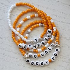 Get ready for game day with our University of Tennessee spirit stack.  Our beaded bracelets are the only accessory you will need to cheer on the Volunteers. Part of our SEC gameday collection. Wear one or stack 'em up.  Goes great with our solid stretch beaded stackers.  Choose from five designs: Tennessee, T, Go Vols, Rocky Top or orange and white stacker. Personalization is also available so get in the name game with a personalized bracelet in UT orange & white. Buy them individually or as a s School Spirit Letter Beads Bracelets Gift, Adjustable Beaded Bracelets For Game Day With School Spirit, School Spirit Jewelry With Letter Beads For Gifts, School Spirit Beaded Bracelets With Letter Beads For Gifts, School Spirit Beaded Bracelet With Letter Beads As Gift, Game Day Bracelets With Letter And Round Beads, Personalized School Spirit Jewelry For Game Day, School Spirit Personalized Jewelry For Game Day, Team Spirit Beaded Bracelets For Game Day