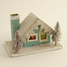 a miniature house with trees and snow on the roof is shown in front of a white background