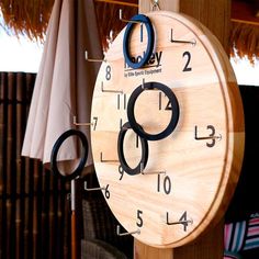 a wooden clock hanging from the side of a building with numbers on it's face