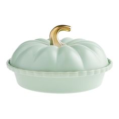 a green pumpkin shaped dish with a gold handle on it's top, sitting in front of a white background