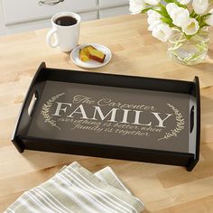 a black tray with the words family on it next to a cup of coffee and napkins