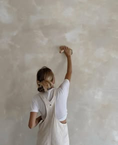 a woman is painting the walls with white paint and she has her hands up in the air