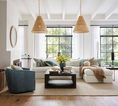 a living room filled with lots of furniture next to large windows and wooden floors in front of them