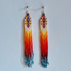 Handmade Huichol Earrings - Intricate Beadwork by Indigenous Artisans from Mexico Handmade by Huichol artisans, an indigenous people of Mexico, these earrings showcase the mastery of fine beadwork that the Huichol are renowned for. This amazing pair features a cascade of powerful colours that has a wonderful effect when wearing them.  ✨ What makes them special? Intricate designs: Each pair is crafted using fine beads and this is what creates these amazing intricate color patterns that reflect Huichol tradition and spirituality. Handmade with care: Every piece is meticulously designed and beaded by hand by Huichol families, making no two pairs exactly alike. Cultural significance: The Huichol people are known for their deep connection to nature, and their art reflects sacred symbols and sto Artisan Hand-strung Earrings For Gift, Artisan Hand-strung Round Bead Earrings, Artisan Hand-strung Dangle Earrings, Traditional Hand-strung Earrings For Gifts, Handmade Southwestern White Earrings, Multicolor Hand-strung Dangle Earrings, Multicolor Hand-strung Bohemian Earrings, Multicolor Bohemian Hand-strung Earrings, Handmade Traditional Orange Beaded Earrings