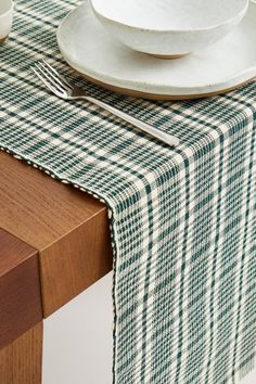 the table is set with plates, silverware and a green checkered tablecloth