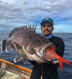 a man on a boat holding a large fish