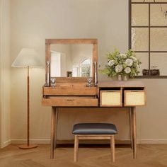 a wooden desk with a mirror, stool and lamp