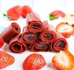 strawberries and rolled up chocolate bars on a white plate with some strawberries in the background