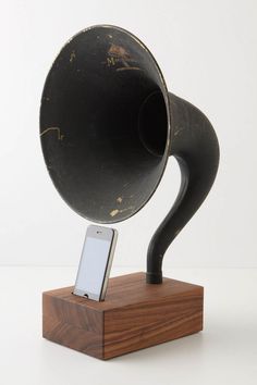 an old, black megaphone on a wooden stand with a cell phone in it