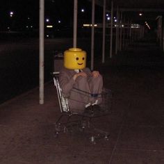 a person sitting in a shopping cart with a smiley face on it's head