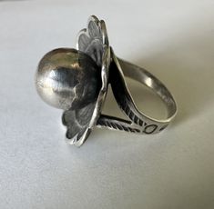 so unusual and so much fun, a southwestern ring with concave flower design and a central orb.  this is unmarked sterling in good condition with light scratching, especially on the orb.  the band is a split style with stampings including arrows.  a wonderful design that i haven't come across before.  i believe it has been sized, but done very well.   size:  6.25 height of face:  15/16" width of inner band:  1/8" height off finger:  7/16" Vintage Silver Concho Ring, Vintage Adjustable Concho Rings, Vintage Concho Ring Jewelry, The Orb, Rings Statement, Flower Design, Flower Designs, The Band, Statement Rings