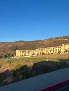 a large building sitting on top of a lush green field next to a mountain range