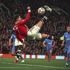 a man kicking a soccer ball in the air with his legs stretched out and feet spread wide