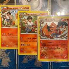 three pokemon cards are on display in a store window, one is orange and the other is blue