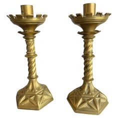 two golden candlesticks are standing next to each other on a white background,