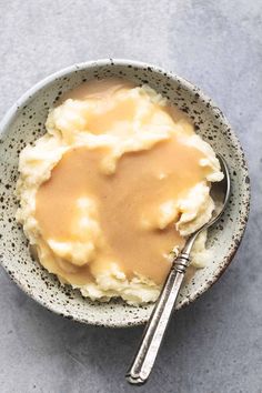 a bowl filled with mashed potatoes and gravy on top of a table