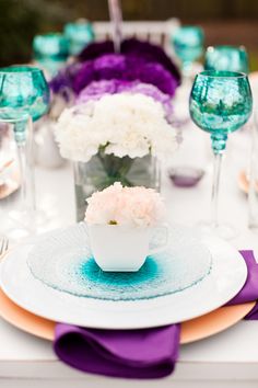 the table is set with purple and white flowers