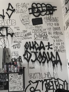 graffiti is on the wall in this room with black and white writing, including words that read