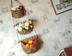 three baskets hanging on the wall with flowers and fruit in them