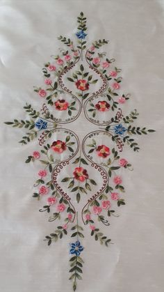 an embroidered white cloth with pink and blue flowers on it