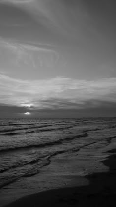 a black and white photo of the ocean at sunset